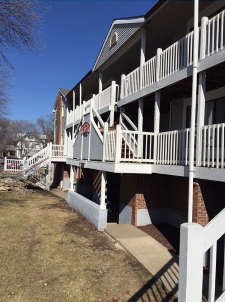Angled front view of an apartment building lined with white balconies and staircases.